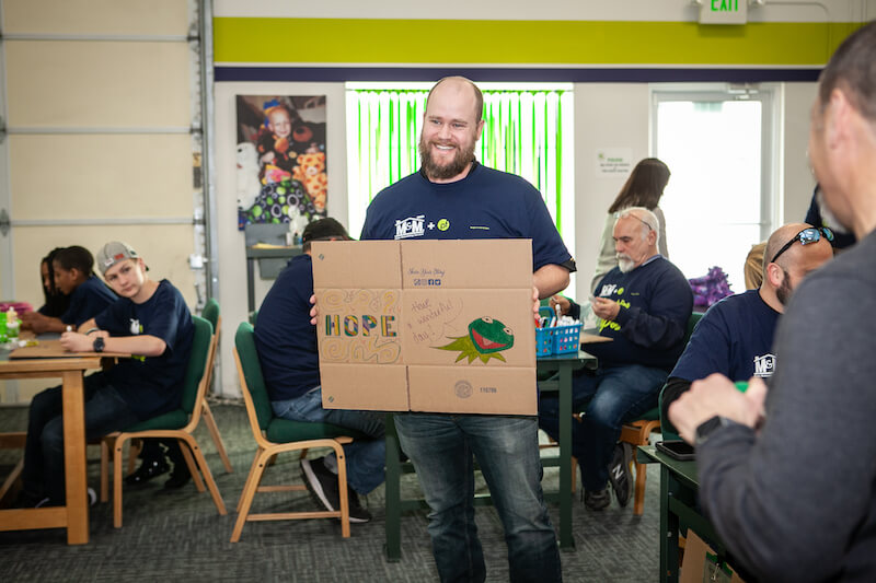 Man smiling while holding a sign that says "hope."








