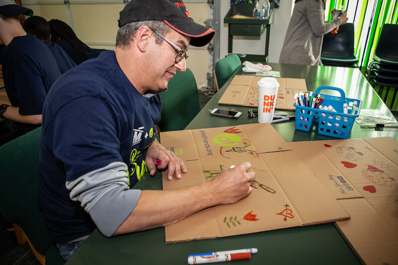 Man writing on a cardboard box.








