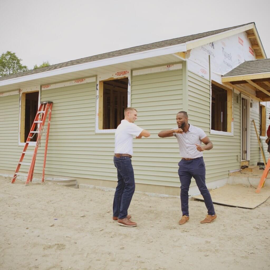 two man standing infront the house they build